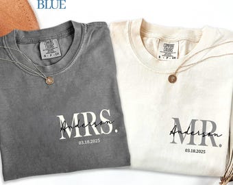 May include: Two Comfort Colors t-shirts, one gray and one cream, with matching gold necklaces. The gray shirt says "MRS. Anderson 03.18.2025" and the cream shirt says "MR. Anderson 03.18.2025". The text "HEAVEN BLUE" is in the top left corner.