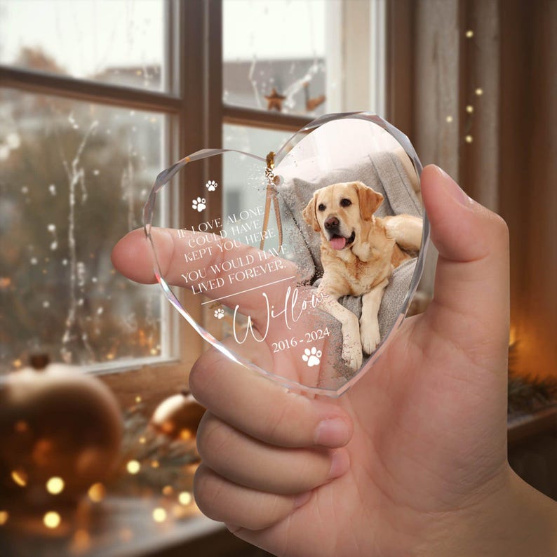 May include: A heart-shaped glass ornament with a photo of a dog inside. The ornament has the text "If love alone could have kept you here you would have lived forever" and "Willow 2016-2024" on it.