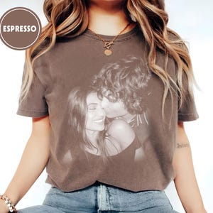 May include: Espresso-coloured t-shirt with a black and white image of a couple. The t-shirt has a crew neck and short sleeves. The word "ESPRESSO" is in a brown circle in the upper left corner.