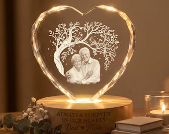 May include: A heart-shaped crystal plaque featuring an etched image of a couple under a tree with birds. The crystal sits on a round wooden base engraved with the text "ALWAYS & FOREVER IN OUR HEARTS Dad ♥ Mom" and is illuminated from below.