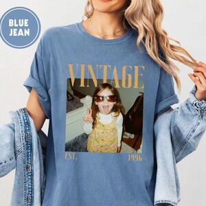 Puede incluir: Camiseta azul vaquero con un gr&aacute;fico de estilo vintage. El gr&aacute;fico presenta una foto de un ni&ntilde;o con gafas de sol sacando la lengua, con la palabra "VINTAGE" arriba y "EST. 1996" abajo.