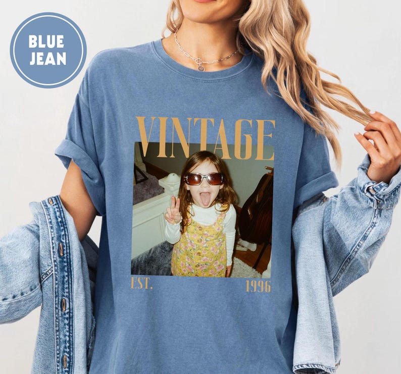 Puede incluir: Camiseta azul vaquero con un gr&aacute;fico de estilo vintage. El gr&aacute;fico presenta una foto de un ni&ntilde;o con gafas de sol sacando la lengua, con la palabra "VINTAGE" arriba y "EST. 1996" abajo.