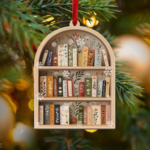 May include: Wooden Christmas ornament shaped as a bookshelf, with miniature books decorated with floral designs. The ornament has a red ribbon for hanging and is decorated with snowflakes. The books are in various colours, including green, yellow, and white.