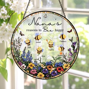 May include: Round glass hanging sign with a black chain, featuring the text "Nana's reasons to Bee happy." The sign has a floral border and illustrations of bees and butterflies. Names are written below each bee.