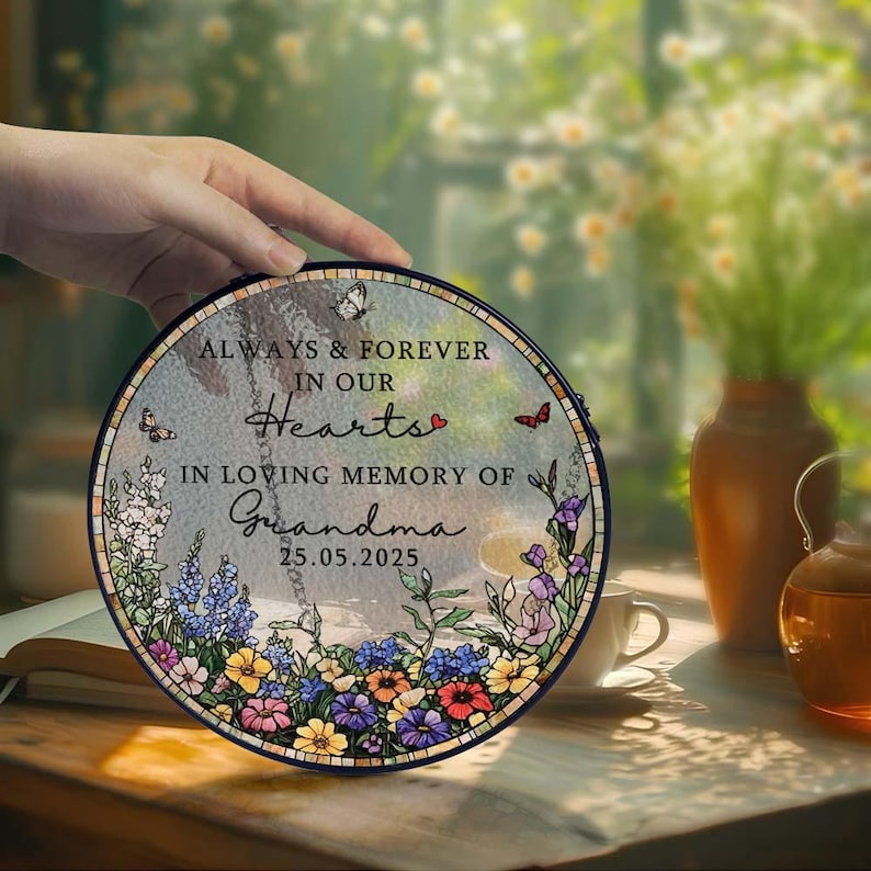 May include: A round memorial plaque with the text "ALWAYS & FOREVER IN OUR Hearts" and "IN LOVING MEMORY OF Grandma 25.05.2025". The plaque features a floral border with butterflies and a heart.
