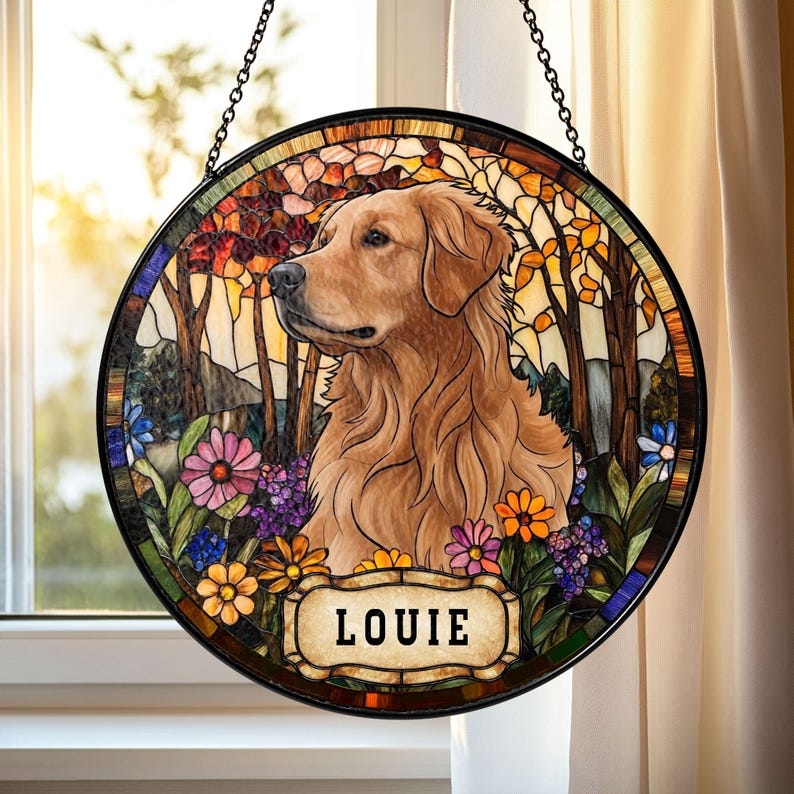 May include: Round stained glass window featuring a golden retriever dog portrait. The artwork includes a colorful floral and forest background with the name "LOUIE" displayed on a banner. The window is framed in black and hangs from a chain.