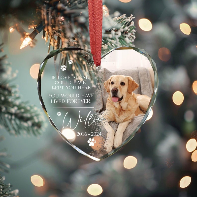 May include: A glass heart-shaped ornament with a photo of a golden retriever dog inside. The ornament has the text "If love alone could have kept you here you would have lived forever." and "Willow 2016-2024" on it.