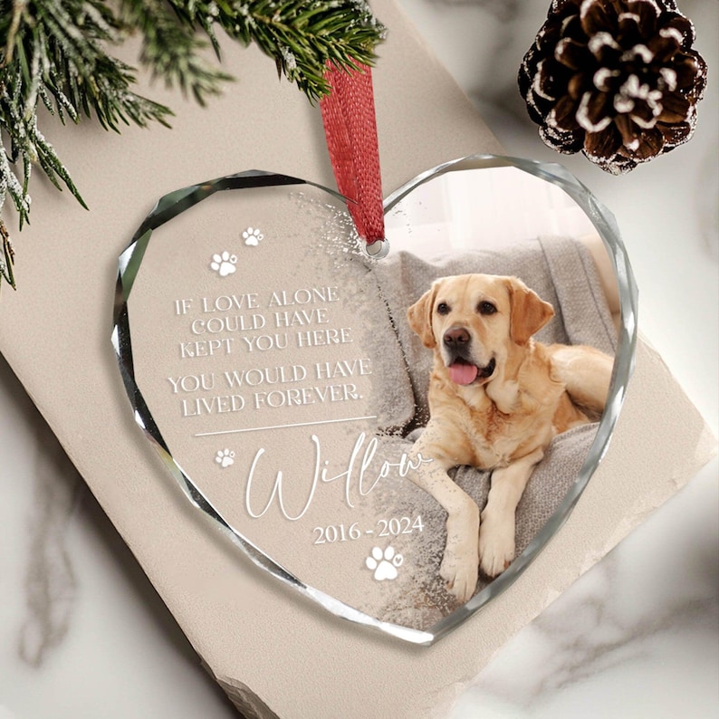 May include: A heart-shaped glass bauble with a photo of a golden retriever dog. The bauble has the text "IF LOVE ALONE COULD HAVE KEPT YOU HERE YOU WOULD HAVE LIVED FOREVER. Willow 2016-2024" on it.