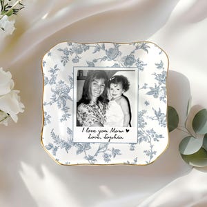 May include: A white and blue floral patterned ceramic dish with a gold rim. The dish holds a black and white photo with the text "I love you Mom Love, Sophia."