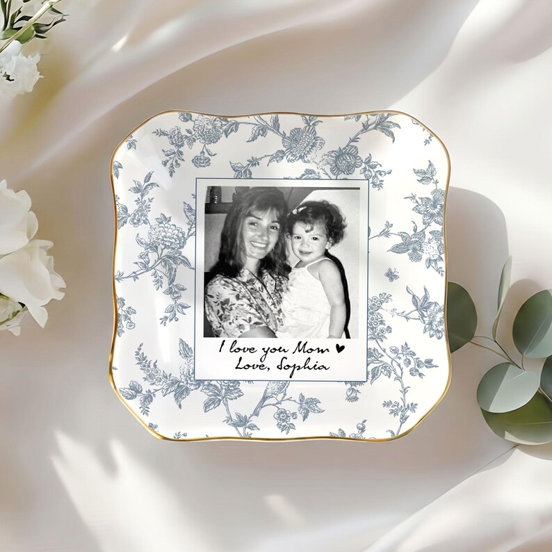 May include: A white and blue floral patterned ceramic dish with a gold rim. The dish holds a black and white photo with the text "I love you Mom Love, Sophia."