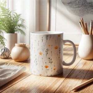 A mug with a dainty floral design with blue, yellow, and white flowers. The main color of the mug is white on the inside and outside.