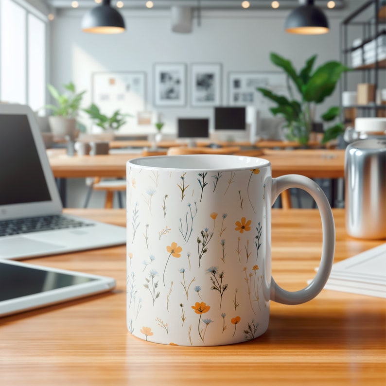A mug with a dainty floral design with blue, yellow, and white flowers. The main color of the mug is white on the inside and outside.