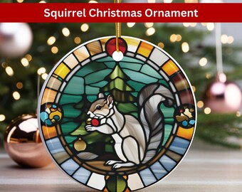 May include: A round ceramic Christmas ornament featuring a stained glass design of a squirrel holding a red berry in front of a green pine tree. The ornament has a gold, blue, and red border.