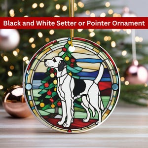 May include: A round ceramic ornament featuring a stained glass design of a black and white setter dog standing in front of a Christmas tree. The ornament has a gold string for hanging.