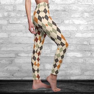 May include: Leggings featuring a repeating argyle pattern in shades of cream, dark brown, muted green, and burnt orange. The fitted garment extends from the waist to the ankles, showcasing a classic diamond-shaped geometric design throughout.