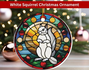 May include: A white squirrel Christmas ornament with a stained glass design. The squirrel is standing on a green base with red ornaments around it. The background is a yellow and orange sunset.