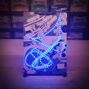 May include: A blue LED light outlines the path of a roller coaster on a white background. The coaster is called "Demon Dive Coaster".