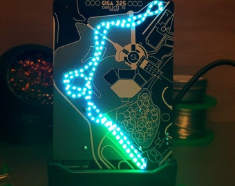 May include: A blue LED circuit board with a map of Charlotte, NC, and the text "GIGA 325 CHARLOTTE, NC 28204" printed on it. The circuit board is lit up with a blue LED light that traces a path around the map.