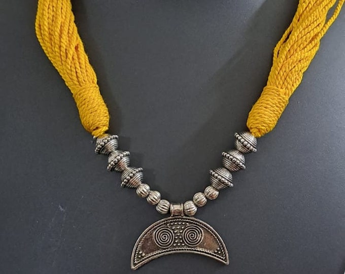 Yellow thread necklace with oxidised silver dokra pendant
