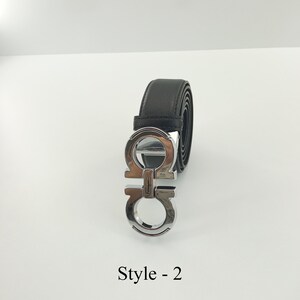 以下が含まれることがあります： シルバーカラーのバックルが付いた黒い革ベルト。バックルはダブルGのデザインです。「Style - 2」の文字が下に印刷されています。