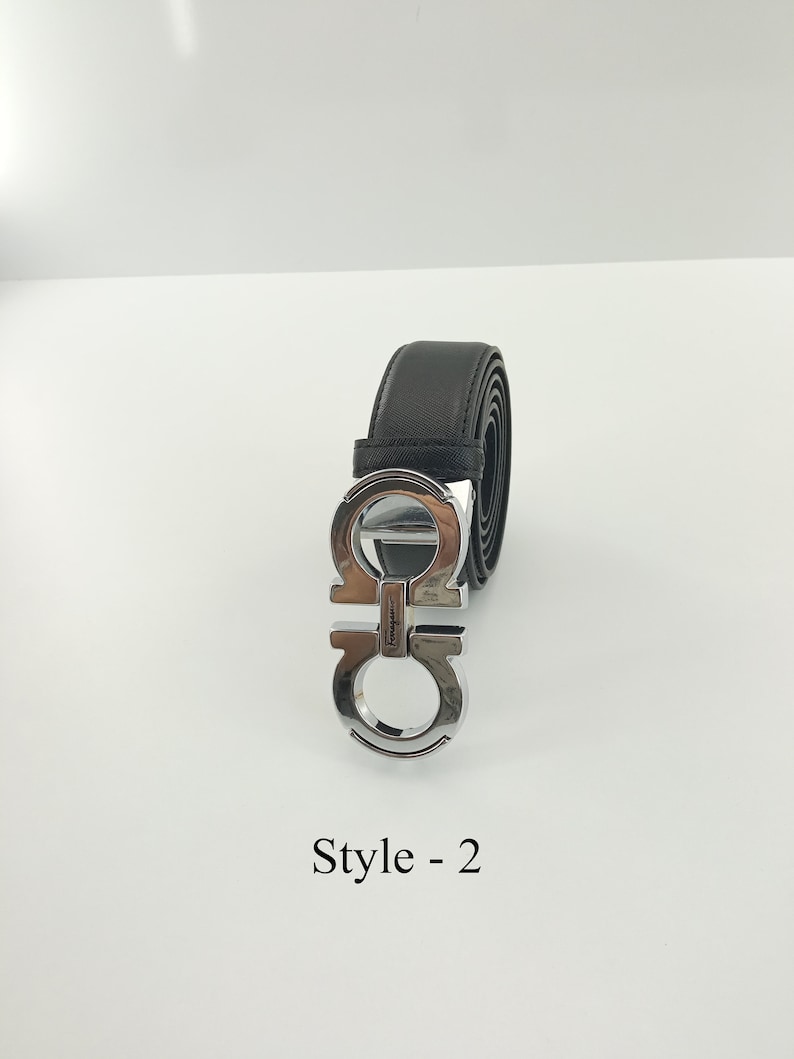 以下が含まれることがあります： シルバーカラーのバックルが付いた黒い革ベルト。バックルはダブルGのデザインです。「Style - 2」の文字が下に印刷されています。