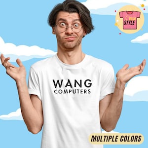 May include: White t-shirt with the text "WANG COMPUTERS" in black. The image shows a person wearing the shirt, with a confused expression and arms outstretched. The background is a blue sky with white clouds. The words "MULTIPLE COLORS" are at the bottom.