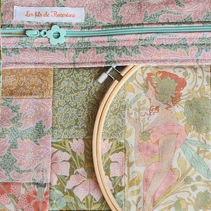 Peut inclure: Une pochette en tissu avec un motif floral dans des tons de rose, vert et doré, dotée d'une fermeture éclair vert clair avec une tirette en forme de fleur. Une étiquette blanche indique Les fils de Florestine. Un tambour à broder en bois.