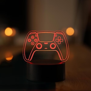 Könnte beinhalten: Ein rot beleuchtetes 3D-gedrucktes Design eines Videospiel-Controllers auf einem schwarzen Sockel.