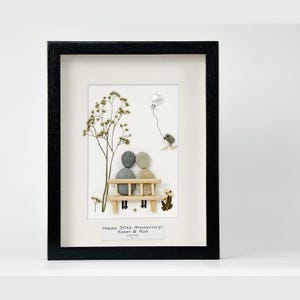 Könnte beinhalten: Gerahmtes Kunstwerk mit einer Kieselkunstszene von zwei Figuren auf einer Bank. Ein Baum und ein Ballon sind ebenfalls dargestellt. Das Kunstwerk ist in einem schwarzen Rahmen und enthält den Text "Happy 30th Anniversary! Susan & Rob".