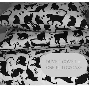 Può includere: Un copripiumino e una federa bianchi con una stampa di gatto bianco e nero. La stampa presenta silhouette di gatti in varie pose, con impronte di zampe sparse su tutto il tessuto. Il testo "DUVET COVER + ONE PILLOWCASE" è stampato in nero su sfondo bianco.