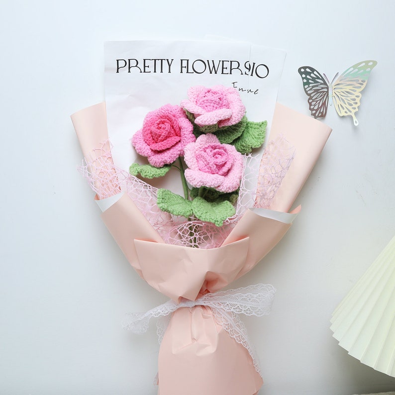 This is a pink themed knitted rose bouquet. Contains 3 pink knitted roses. Green cotton thread is wrapped around wire to create a rhizome with three leaves on the rhizome. The wrapping paper is pink and the ribbon is white