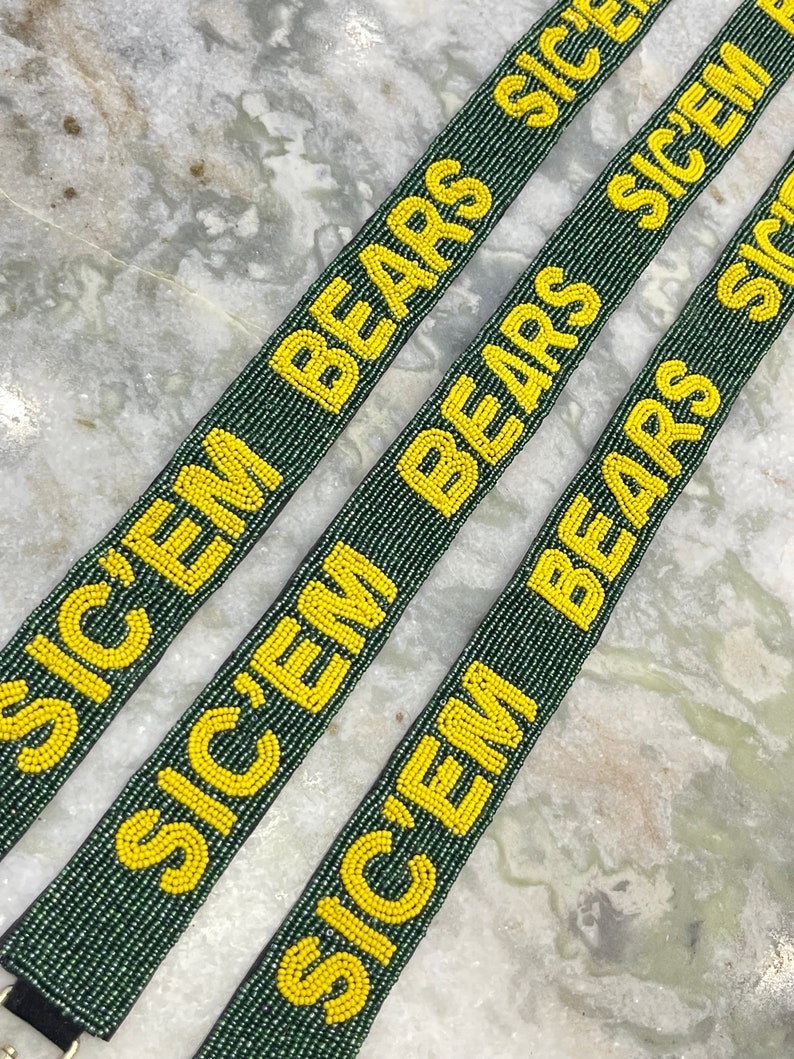 Puede incluir: Tres correas de cuentas verdes y amarillas con el texto "Sic 'Em Bears" repetido en cada correa.