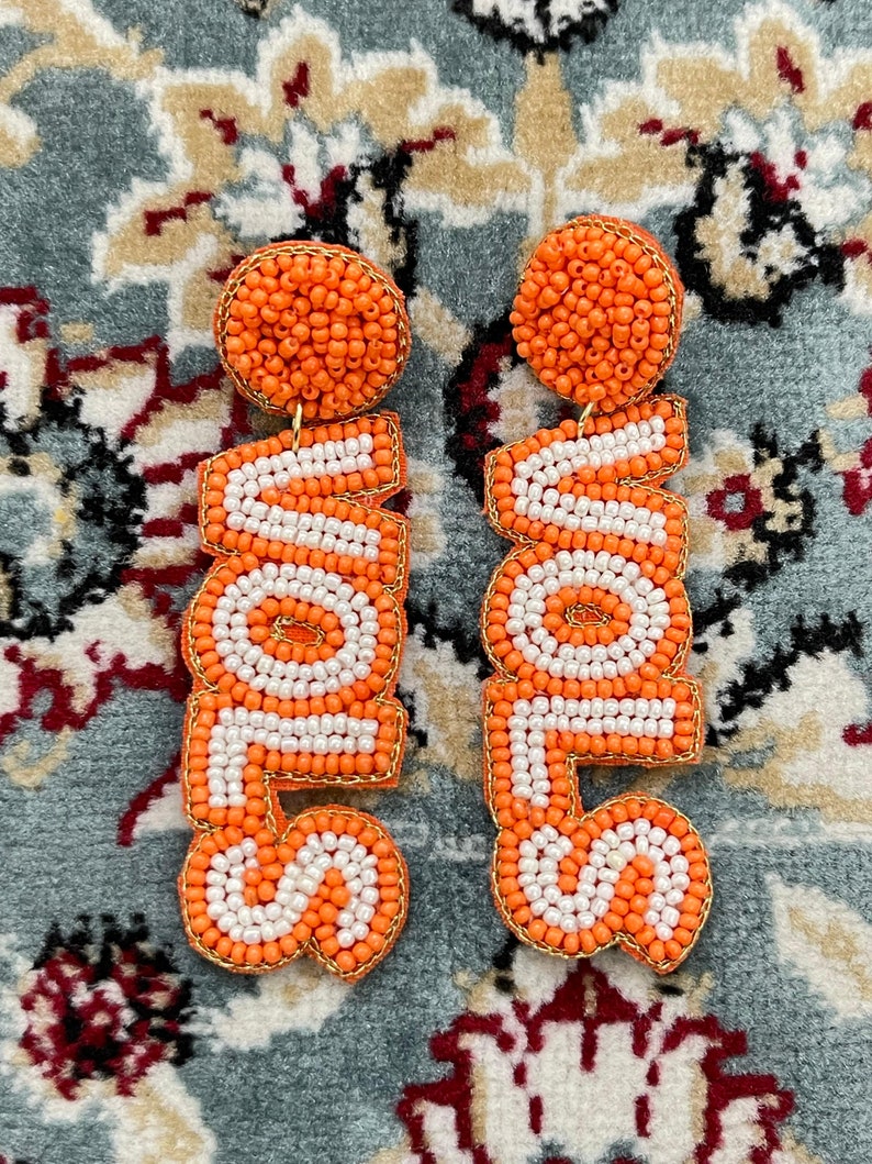 May include: A pair of orange and white beaded earrings that spell out the word "LOVE".