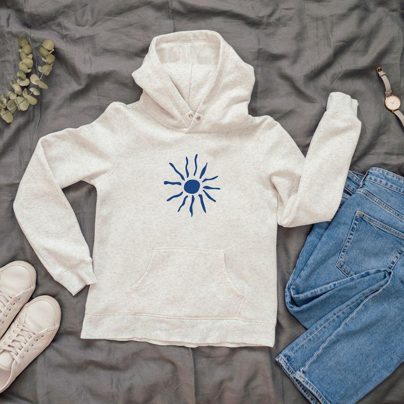 May include: A light gray hoodie with a blue sun graphic on the front. The hoodie has a drawstring hood and a kangaroo pocket.