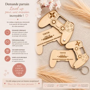 Könnte beinhalten: Holz-Schlüsselanhänger und Anhänger in Form von Gamecontrollern. Die Controller haben gravierte Knöpfe und den Text "TONTON LEVEL UP PARRAIN NOUVEAU PERSONNAGE DÉBLOQUÉ". Das Design beinhaltet ein Herz und das Wort "TOURNE".