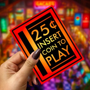 May include: Red and yellow arcade game sign with the text "25¢ Insert Coin to Play".