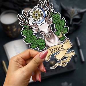 May include: A sticker featuring a white deer with antlers, a crescent moon and sun, and a green oak leaf wreath. The sticker has a banner with the word "Druid" written on it.