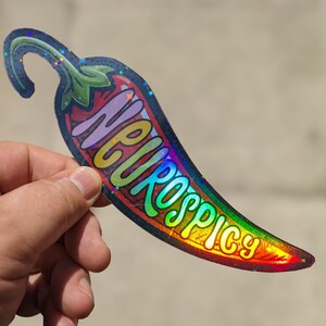 Może przedstawiać: Holograficzna naklejka w tęczowych kolorach przedstawiająca czerwoną papryczkę chili z napisem "Super Spicy".