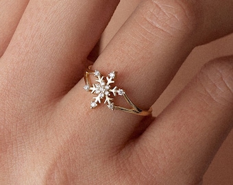 May include: A gold ring with a snowflake design set with clear cubic zirconia stones.
