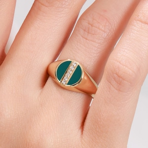 Peut inclure: Une bague signet en or avec un dessus ovale en émail vert et une rangée de pierres claires.