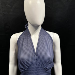 May include: A halter top with a navy blue background and white polka dots. The top has a V-neckline and a halter strap.