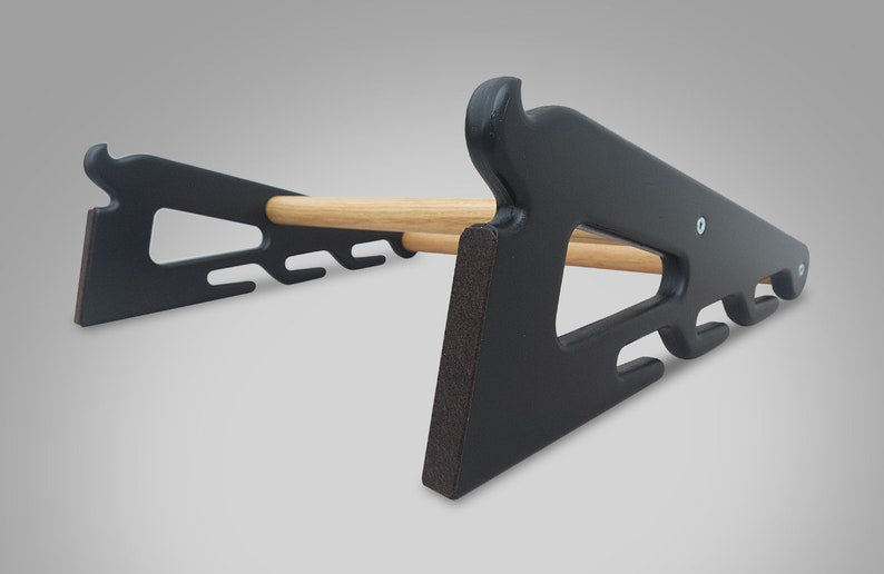 May include: A black wooden rack with a natural wood dowel. The rack has a unique design with cut-out shapes and a curved top. The rack is designed to hold items and has a sturdy base. The rack is made of wood and has a matte finish.