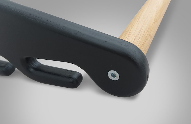 May include: Close-up of a black wooden clothes hanger with a natural wood dowel. The hanger features a curved design with a hook and a metal screw for assembly. The wooden dowel is light brown.