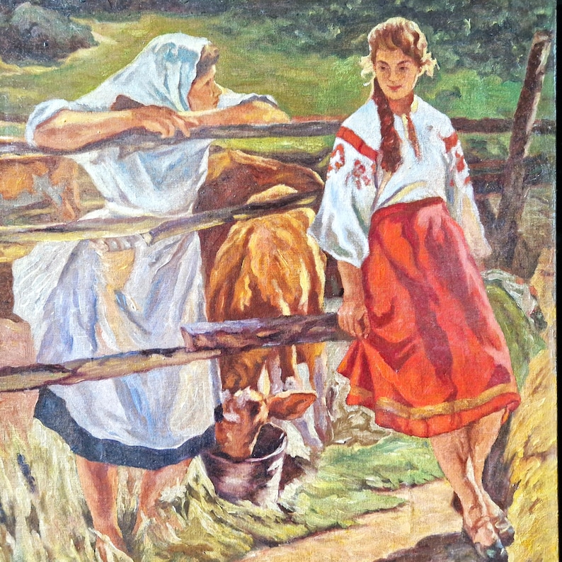 K&ouml;nnte beinhalten: Zwei Frauen in traditioneller Kleidung stehen an einem Holzzaun mit einem braunen Kalb. Die Frau links tr&auml;gt ein wei&szlig;es Kopftuch und ein langes wei&szlig;es Kleid. Die Frau rechts tr&auml;gt eine wei&szlig;e Bluse mit roten Stickereien und einen roten Rock. Das Kalb trinkt aus einem Eimer.