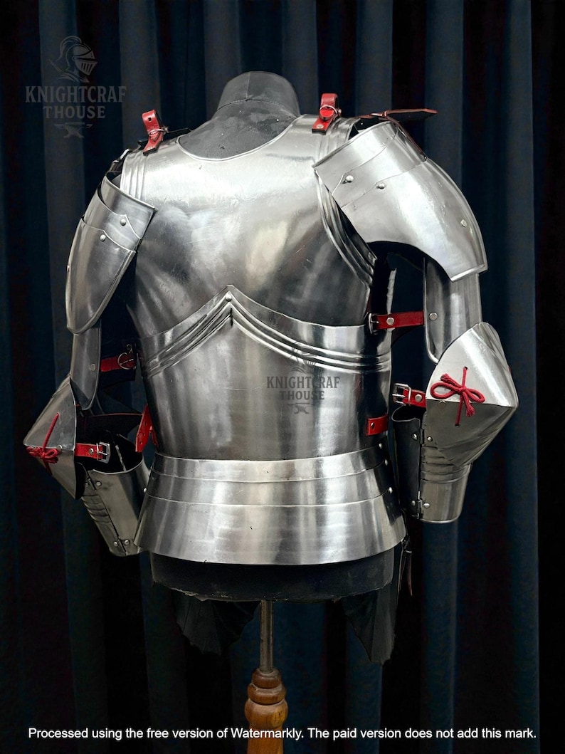 May include: Polished steel armor set, featuring a breastplate, shoulder guards, and arm protection. Red leather straps and accents secure the pieces. The armor is displayed on a mannequin. The text "KNIGHTCRAFT HOUSE" is visible.