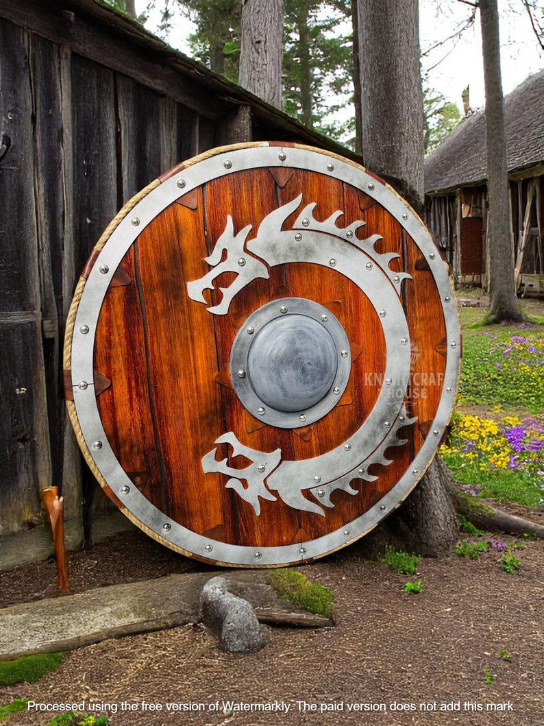 May include: A large, round wooden shield with a metal rim and two dragon designs. The shield is decorated with metal rivets and has a smaller metal circle in the center.
