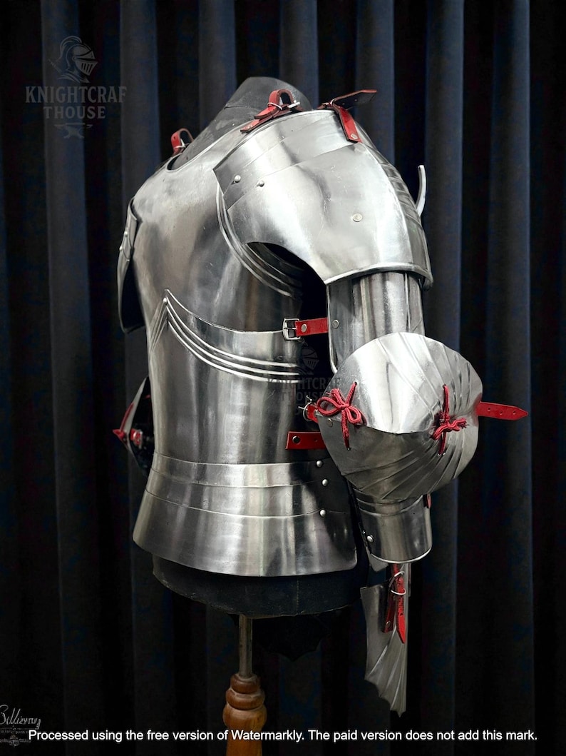 May include: A polished steel breastplate and arm armor with red leather straps and accents. The armor is displayed on a mannequin, showcasing its intricate design and craftsmanship. The image includes the text "KNIGHTCRAFT HOUSE".