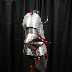 May include: Polished metal armor with red leather straps and accents. The armor is displayed on a mannequin, showcasing the intricate design and craftsmanship. The image includes the text "KNIGHTCRAF THOUSE".