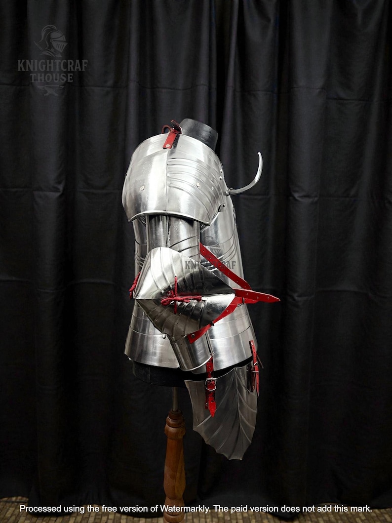 May include: Polished metal armor with red leather straps and accents. The armor is displayed on a mannequin, showcasing the intricate design and craftsmanship. The image includes the text "KNIGHTCRAF THOUSE".