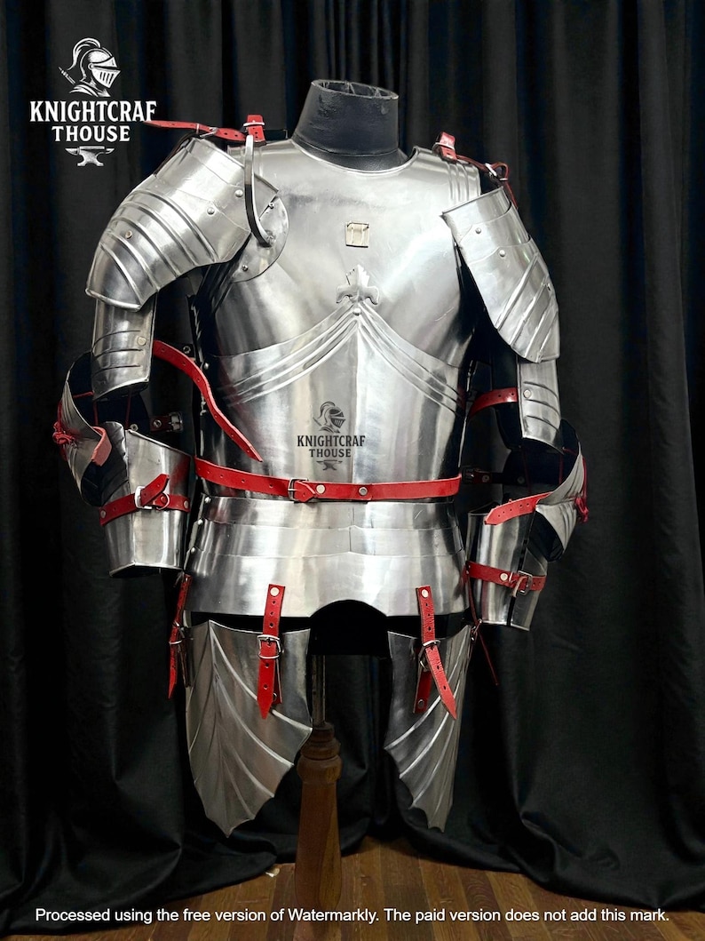 May include: A full suit of polished steel armor with red leather straps and accents. The armor is displayed on a mannequin, showcasing its intricate design and craftsmanship. The Knightcrafthouse logo is visible.